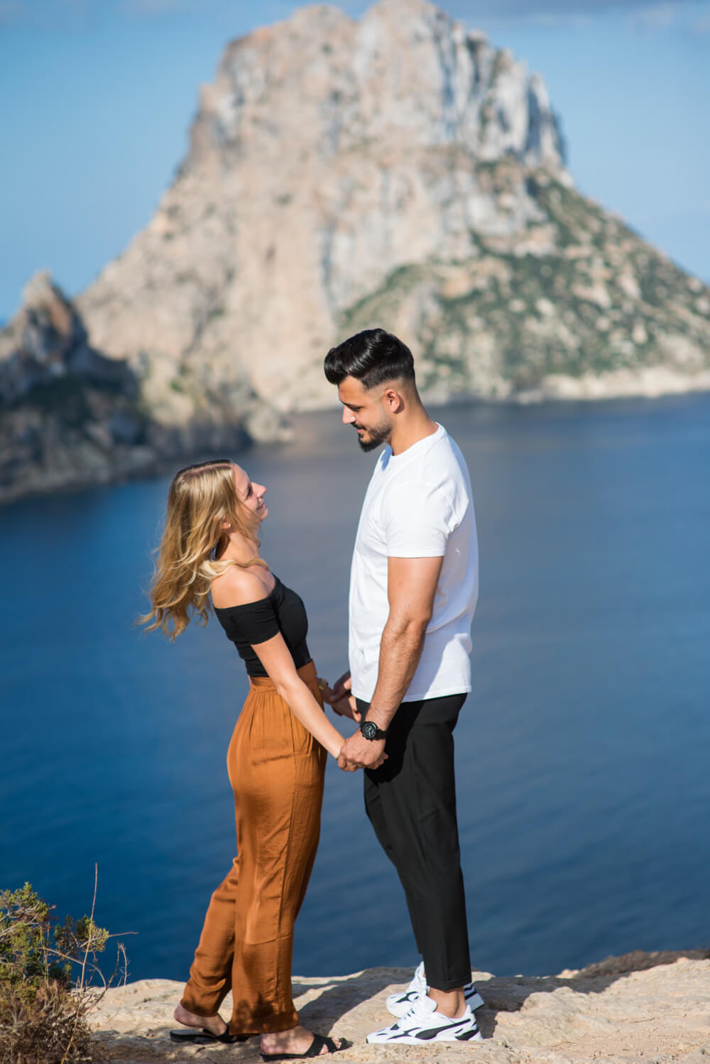 couple holding hands and gazing at eachother on a cliff