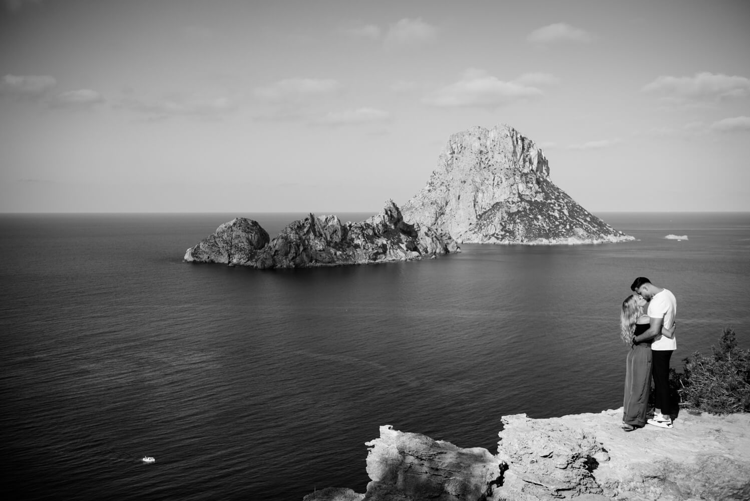 black and white photo of a couple staring out to an island in the distance