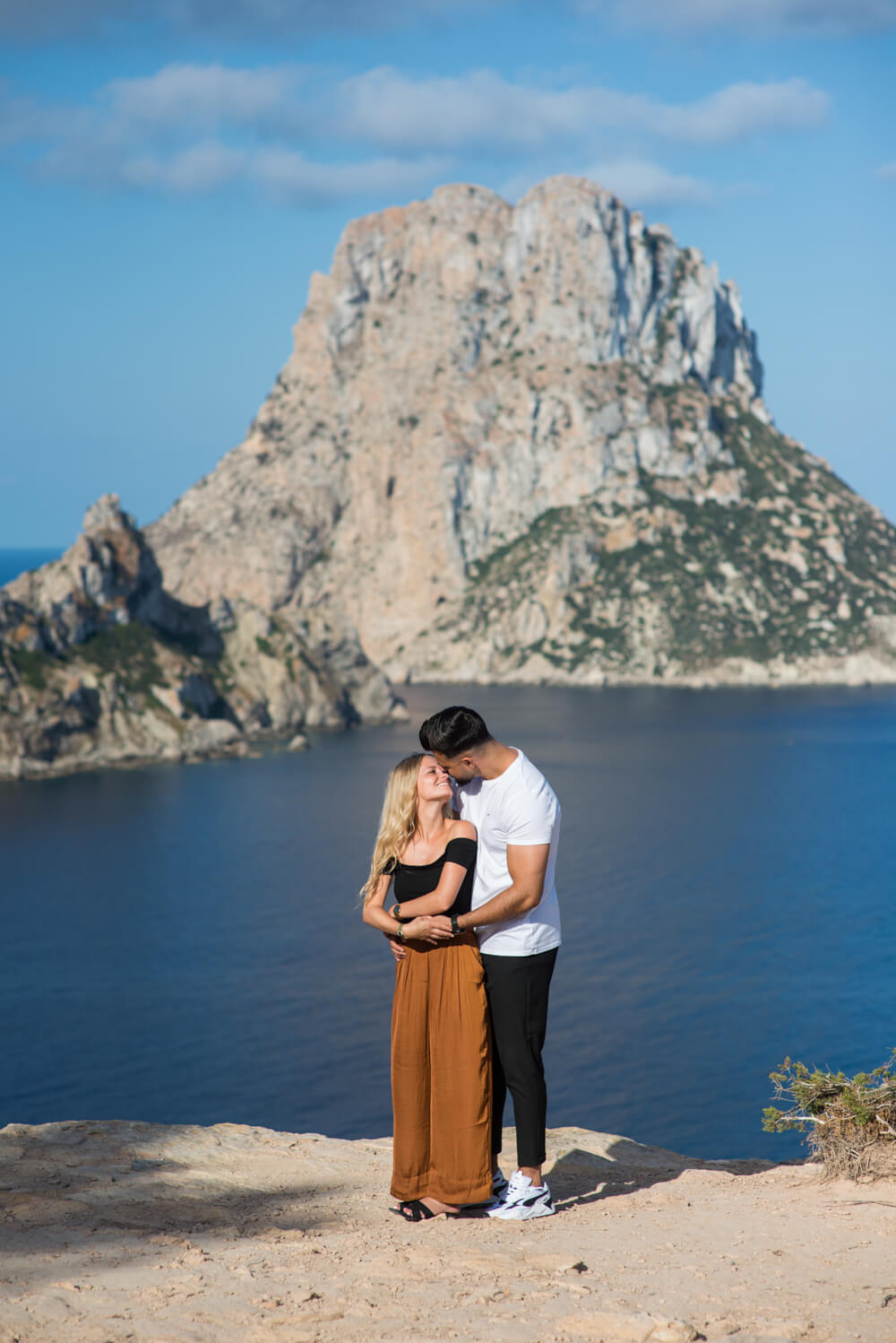 a couple about to kiss in front of an island landmark
