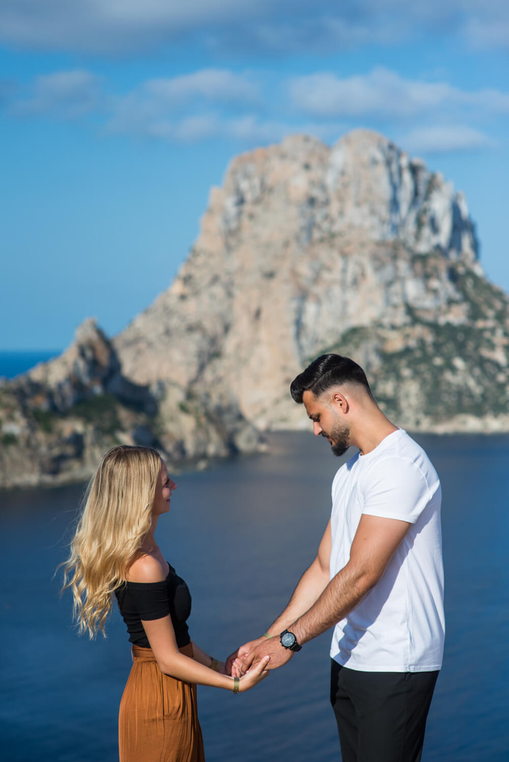 couple holding hands with an island in the background