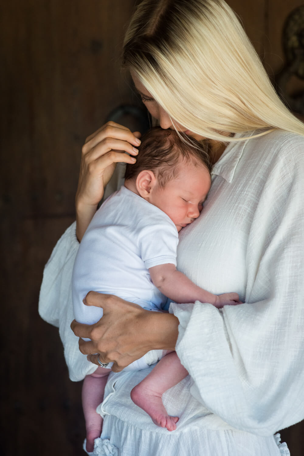 blonde mother holding her sleeping newborn son