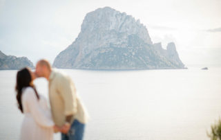 Couple kissing during their Pregnancy Shoot looking over Es Vedra